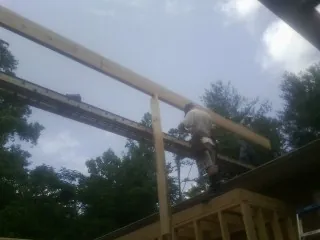 Carpenter setting a ridge beam over a new addition frame — Ice Dam Removal by Roofing Brothers in Margarettsville
