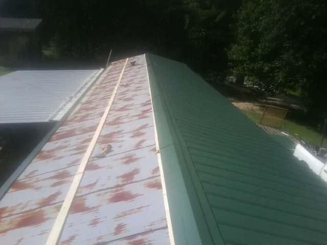 Old rusted panels beside newly installed green metal roofing — Wind Damage Roof Repair by Roofing Brothers in Margarettsville