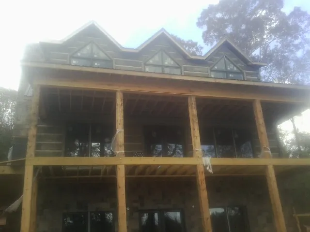 Dormers and porch framing on a large log home under construction — Roof Coating work by our crew in Margarettsville