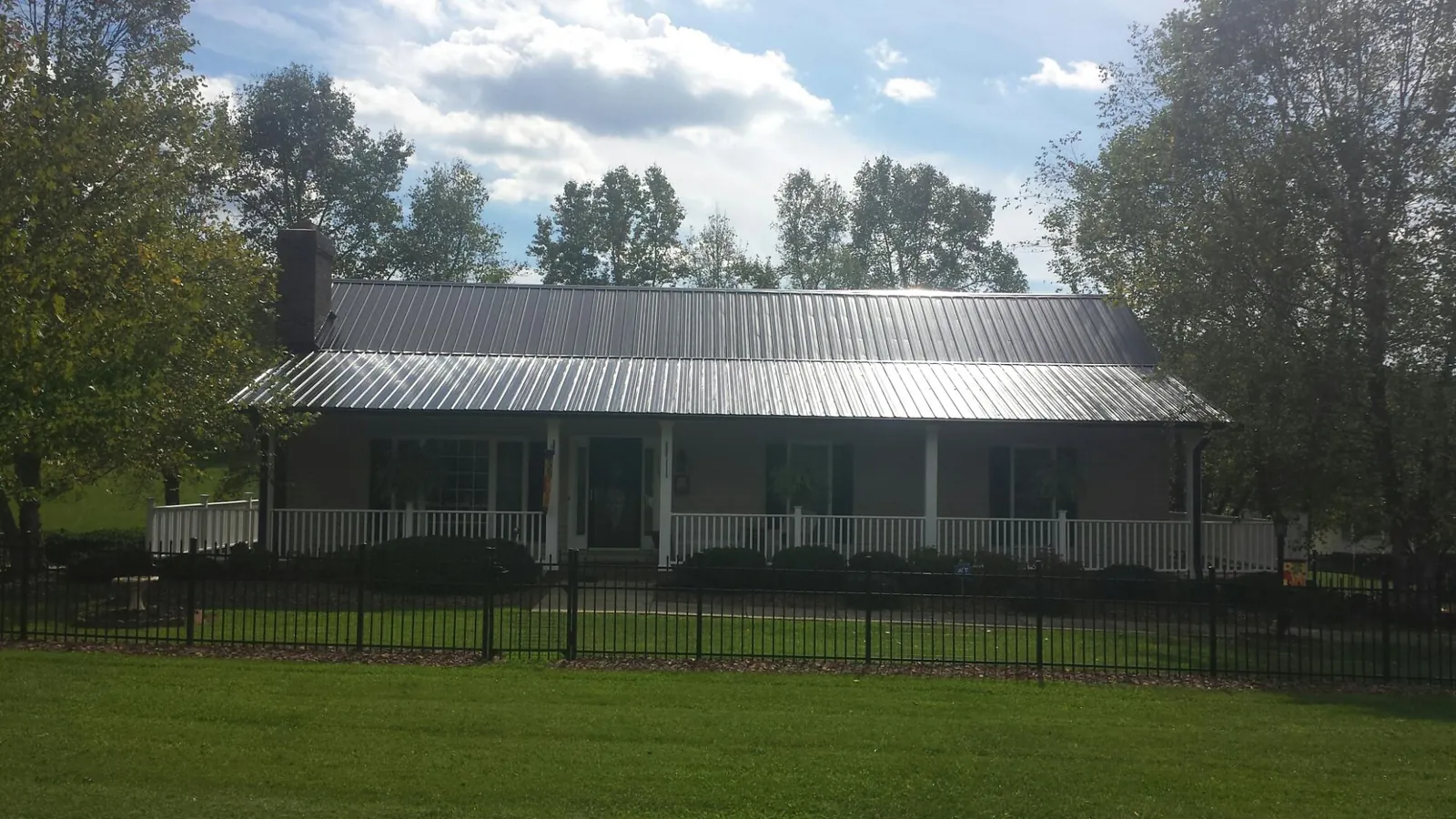 Gray metal roof on a brick ranch with a full width front porch — Gutter Guard Installation work by our crew in Margarettsville