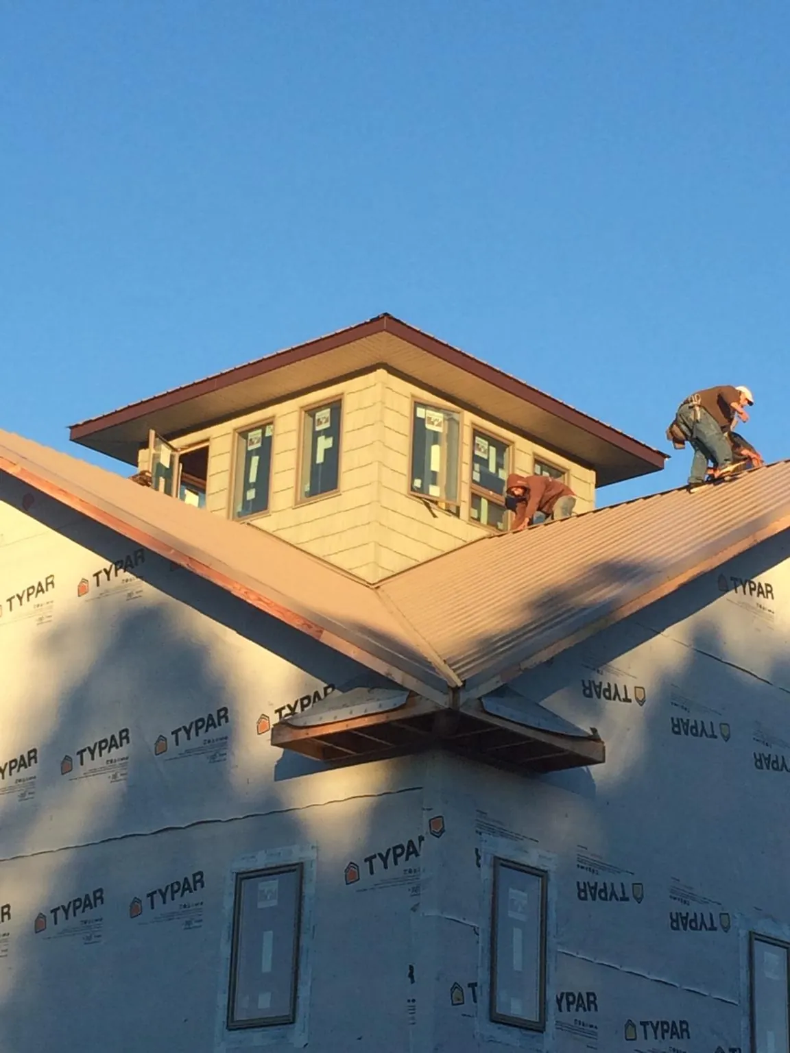 Roofers working around a rooftop cupola on a new metal roof at sunset — Roof Waterproofing in Margarettsville by Roofing Brothers